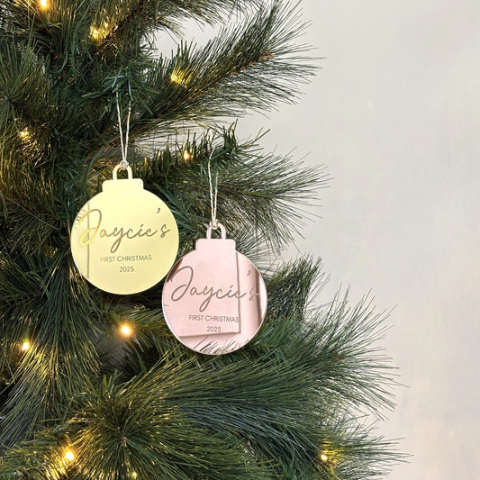 Two Christmas ornaments on a decorated tree with a light gray background